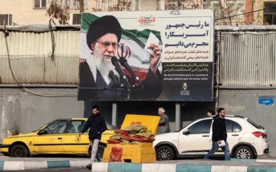 Des Iraniens passent devant un panneau d'affichage montrant le guide suprême iranien, l'ayatollah Ali Khamenei, avec des slogans anti-américains, à Téhéran, le 27 janvier 2026. (Crédit : Atta Kenare/AFP)