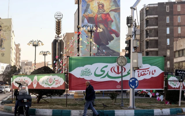 Des banderoles aux couleurs du drapeau iranien ornant un rond-point tandis qu'un homme passe devant, dans la capitale iranienne Téhéran, , à l'approche du 47e anniversaire de la révolution islamique de 1979, le 31 janvier 2026. (Crédit : Atta Kenare/AFP) Des banderoles aux couleurs du drapeau iranien ornant un rond-point tandis qu'un homme passe devant, dans la capitale iranienne Téhéran, , à l'approche du 47e anniversaire de la révolution islamique de 1979, le 31 janvier 2026. (Crédit : Atta Kenare/AFP)