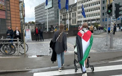 Une femme portant un drapeau palestinien pousse une poussette sur un passage piéton devant le siège de l'UE à Bruxelles, le 26 mai 2024. (AP/Virginia Mayo)