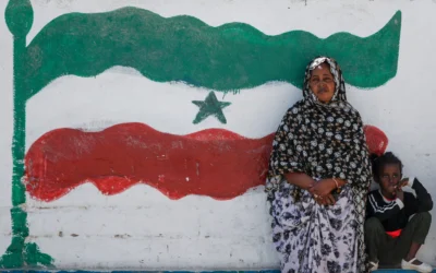 Une femme et une enfant assises devant une fresque représentant le drapeau du Somaliland, à Hargeisa, au Somaliland, une région semi-autonome séparée de la Somalie, le 9 février 2022. (Crédit : Brian Inganga/AP Photo)