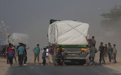 Illustration : Des Gazaouis se précipitant vers des camions transportant de l'aide humanitaire alors qu'ils traversent Deir al-Balah, dans le centre de Gaza, le 9 novembre 2025. (Crédit : Jehad Alshrafi/AP) Illustration : Des Gazaouis se précipitant vers des camions transportant de l'aide humanitaire alors qu'ils traversent Deir al-Balah, dans le centre de Gaza, le 9 novembre 2025. (Crédit : Jehad Alshrafi/AP)