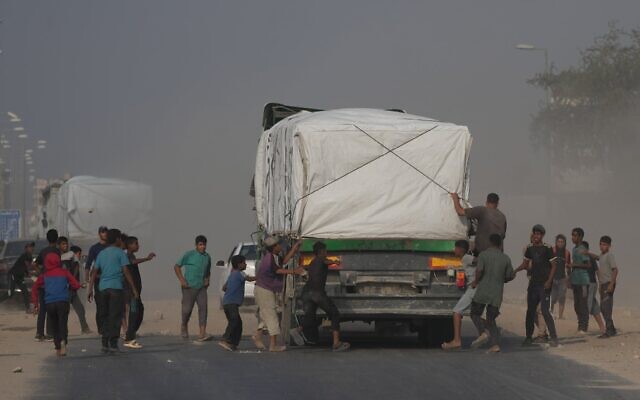 Illustration : Des Gazaouis se précipitant vers des camions transportant de l'aide humanitaire alors qu'ils traversent Deir al-Balah, dans le centre de Gaza, le 9 novembre 2025. (Crédit : Jehad Alshrafi/AP)