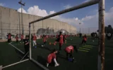 Des fillettes palestiniennes participent à un entraînement de football sur un terrain situé à côté de la barrière de sécurité israélienne dans le camp de réfugiés d'Aida, dans la ville de Bethléem, en Cisjordanie, le 26 décembre 2025. (Crédit : AP Photo/Mahmoud Illean)