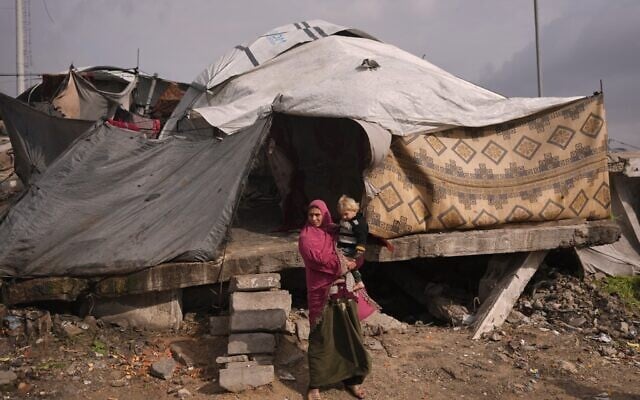 Illustration : Une femme tenant un enfant dans ses bras devant leur tente dans un camp de fortune pour Palestiniens déplacés installé dans un quartier de Gaza City, le 29 décembre 2025. (Crédit : Jehad Alshrafi/AP Photo)