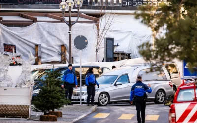 Un corbillard passant devant des policiers qui inspectent la zone où un incendie s’est déclaré au bar-salon La Constellation pendant les célébrations du Nouvel An à Crans-Montana, en Suisse, le 1ᵉʳ janvier 2026. (Crédit : Jean-Christophe Bott/Keystone/AP)