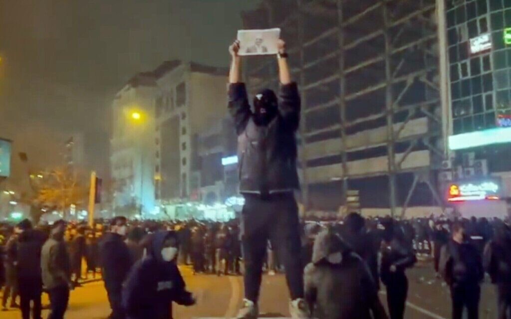 Un manifestant masqué tenant une photo du prince héritier iranien Reza Pahlavi lors d'une manifestation, à Téhéran, en Iran, le 9 janvier 2026. (Crédit : Capture d’écran/UGC via AP)