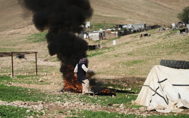 Un habitant palestinien du village de Ras Ein al-Auja, en Cisjordanie, brûle des déchets, le 11 janvier 2026. (Crédit : AP Photo/Mahmoud Illean)