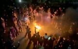 Cette image tirée d'une vidéo diffusée sur les réseaux sociaux montre des manifestants dansant et applaudissant autour d'un feu de joie alors qu'ils descendent dans les rues malgré une répression de plus en plus intense, alors que la république islamique reste coupée du reste du monde, à Téhéran, en Iran, le 9 janvier 2026. (Crédit : UGC via AP)