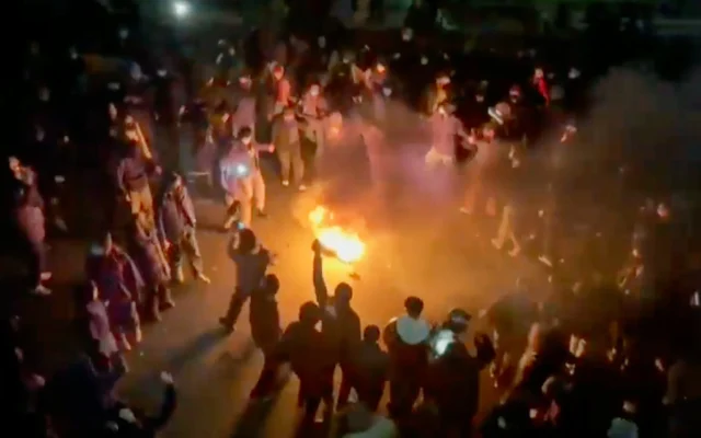 Cette image tirée d'une vidéo diffusée sur les réseaux sociaux montre des manifestants dansant et applaudissant autour d'un feu de joie alors qu'ils descendent dans la rue malgré une répression de plus en plus intense, la république islamique restant coupée du reste du monde, à Téhéran, en Iran, le 9 janvier 2026. (Crédit : UGC via AP)