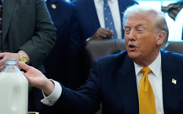 Le président américain Donald Trump montre un bidon de lait avant de signer un projet de loi qui réintroduit le lait entier dans les cantines scolaires à travers le pays, dans le Bureau ovale de la Maison Blanche, mercredi 14 janvier 2026, à Washington. (Crédit : AP Photo/Alex Brandon)