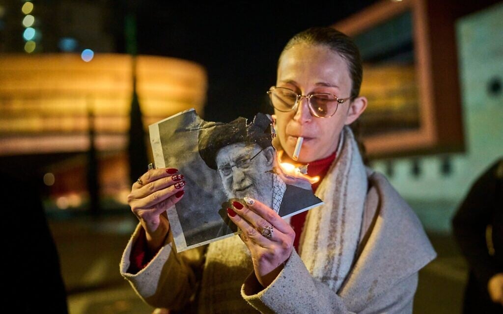Une manifestante allume une cigarette avec une affiche en feu représentant le guide suprême l'ayatollah Ali Khamenei lors d'un rassemblement en soutien aux manifestations antigouvernementales en Iran, à Holon, en Israël, le mercredi 14 janvier 2026. (Crédit : AP/Ohad Zwigenberg) Une manifestante allume une cigarette avec une affiche en feu représentant le guide suprême l'ayatollah Ali Khamenei lors d'un rassemblement en soutien aux manifestations antigouvernementales en Iran, à Holon, en Israël, le mercredi 14 janvier 2026. (Crédit : AP/Ohad Zwigenberg)