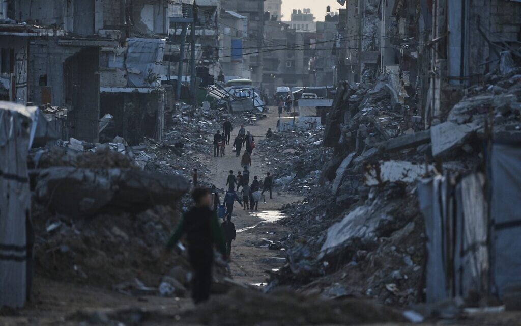 Illustration : des Palestiniens marchent au milieu des bâtiments détruits à Gaza-City, dans le nord de Gaza, le 15 janvier 2026. (Crédit : AP Photo/Jehad Alshrafi) Illustration : des Palestiniens marchent au milieu des bâtiments détruits à Gaza-City, dans le nord de Gaza, le 15 janvier 2026. (Crédit : AP Photo/Jehad Alshrafi)