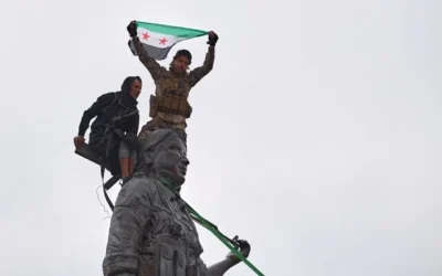 Des soldats du gouvernement syrien agitent un drapeau syrien depuis le sommet de la statue d'une combattante kurde, suite à la prise de contrôle de la ville par les Forces démocratiques syriennes (FDS) soutenues par les États-Unis lors d'une offensive contre les forces dirigées par les Kurdes, à Tabqa, dans l'est de la Syrie, le 18 janvier 2026. (Photo AP / Omar Albam) Des soldats du gouvernement syrien agitent un drapeau syrien depuis le sommet de la statue d'une combattante kurde, suite à la prise de contrôle de la ville par les Forces démocratiques syriennes (FDS) soutenues par les États-Unis lors d'une offensive contre les forces dirigées par les Kurdes, à Tabqa, dans l'est de la Syrie, le 18 janvier 2026. (Photo AP / Omar Albam)