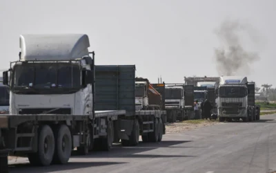 Des camions commerciaux palestiniens, qui attendent l’autorisation de recevoir une cargaison de marchandises destinées à la vente dans l’enclave, sont garés dans une zone de Deir al-Balah, près du passage frontalier de Kissufim dans la bande de Gaza, en, le 27 janvier 2026. (Crédit : Abdel Kareem Hana/AP)