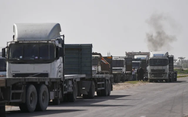 Des camions commerciaux palestiniens, qui attendent l’autorisation de recevoir une cargaison de marchandises destinées à la vente dans l’enclave, sont garés dans une zone de Deir al-Balah, près du passage frontalier de Kissufim dans la bande de Gaza, en, le 27 janvier 2026. (Crédit : Abdel Kareem Hana/AP)