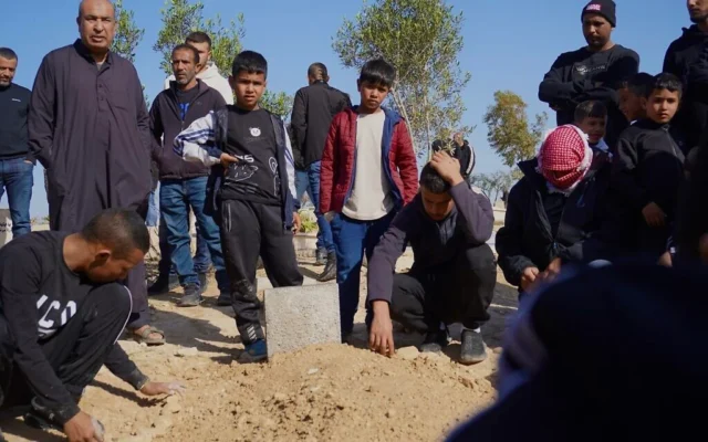 Les enfants de Muhammad Hussein Tarabin, Bédouin tué par des tirs de la police à Tarabin al-Sana, dans le Neguev, se tiennent près de sa tombe après son inhumation, le 5 janvier 2026. (Charlie Summers/Times of Israel)