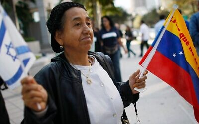 Une femme tenant des drapeaux d'Israël et vénézuéliens pour manifester sa solidarité avec la communauté juive vénézuélienne après une attaque contre une synagogue de Caracas, devant le consulat du Venezuela, à Miami, le 13 février 2009. (Crédit : Joe Raedle/Getty Images via JTA)
