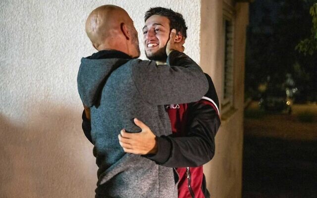 Liam Or-Nassar, otage libéré de Gaza, dans les bras de son père Ramzi Nassar à la base aérienne de Hatzerim, tôt le matin du 30 novembre 2023. (Crédit : Unité du porte-parole de l'armée israélienne)