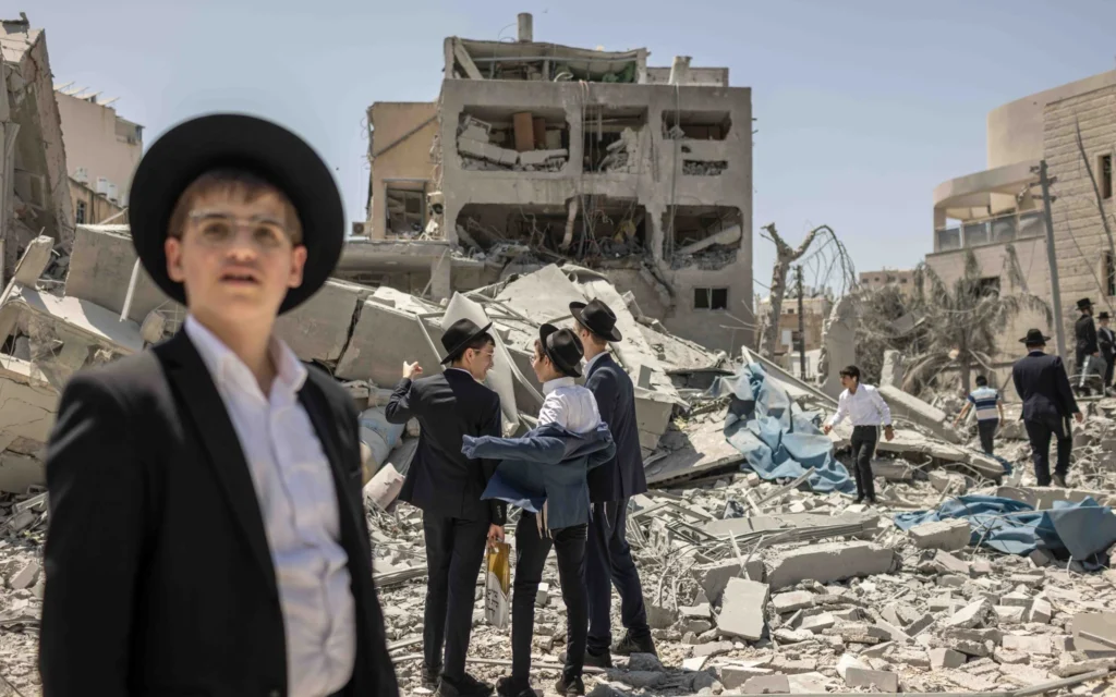 De jeunes hommes ultra-orthodoxes observant les dégâts causés à un immeuble et à une école par un missile iranien qui a frappé Bnei Brak le 16 juin 2025. (Crédit : Avishag Shaar-Yashuv pour le New York Times)