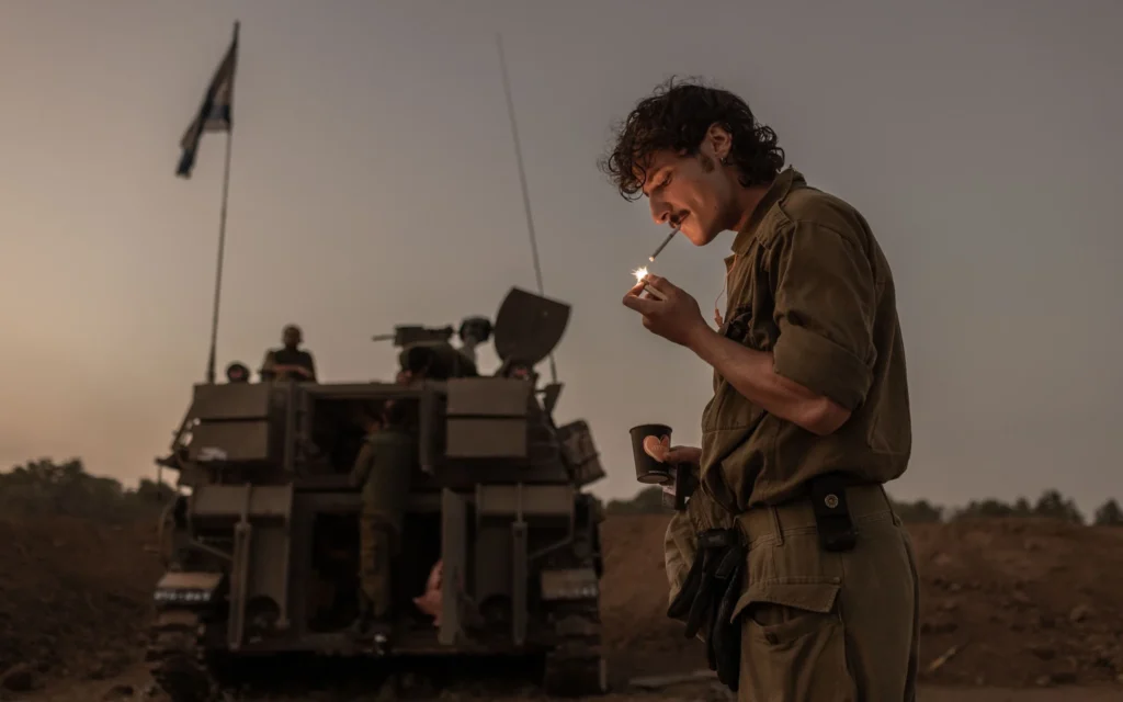 Un soldat israélien allumant une cigarette dans une unité du Corps d’Artillerie, près de la frontière avec Gaza, le 2 novembre 2023. (Crédit : Avishag Shar-Yashuv pour le New York Times)