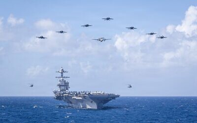 Des avions de la 8e escadre aérienne embarquée de l'US Navy volent en formation au-dessus du plus grand porte-avions au monde, le porte-avions de classe Ford USS Gerald R. Ford (CVN 78), lors de la cérémonie de passation de commandement de la 8e escadre aérienne embarquée, en mer des Caraïbes, le 19 janvier 2026. (Crédit : US Navy)