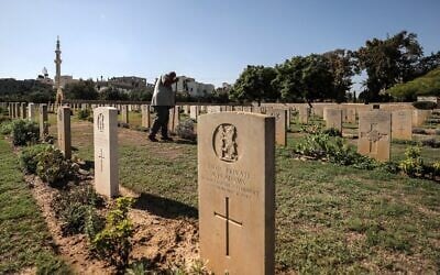 Un jardinier s'occupant de la pelouse entre les pierres tombales du cimetière militaire du Commonwealth de Gaza, communément appelé cimetière militaire britannique, où reposent les dépouilles de 3 217 soldats alliés morts pendant la Première Guerre mondiale, à Gaza-City, le 28 septembre 2022. (Crédit : Mahmud Hams/AFP)