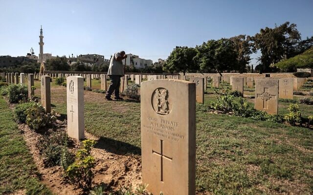 Un jardinier s'occupant de la pelouse entre les pierres tombales du cimetière militaire du Commonwealth de Gaza, communément appelé cimetière militaire britannique, où reposent les dépouilles de 3 217 soldats alliés morts pendant la Première Guerre mondiale, à Gaza-City, le 28 septembre 2022. (Crédit : Mahmud Hams/AFP)