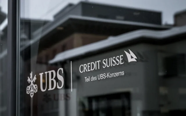 Une enseigne de Credit Suisse indiquant en allemand « membre du groupe UBS », affichée sur une succursale du géant bancaire suisse UBS, dans la station balnéaire de Saint-Moritz, le 20 décembre 2024. (Crédit : Fabrice Coffrini/AFP)