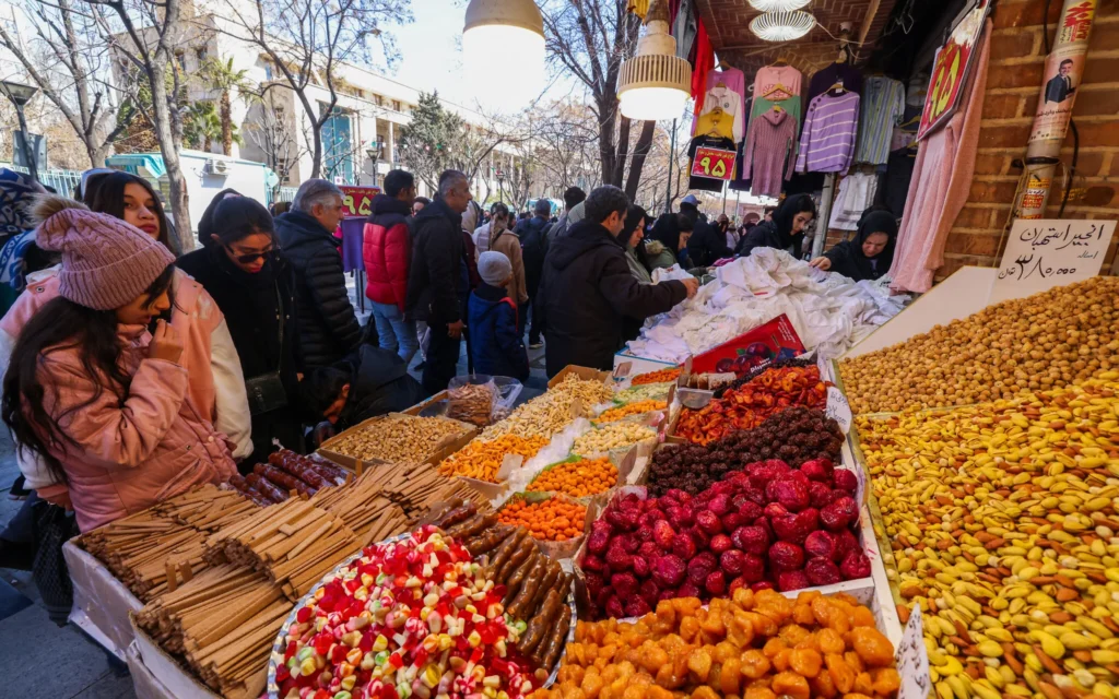 Des clients achètent des fruits secs dans une échoppe du Grand Bazar de Téhéran, en Iran, le 3 mars 2025. (Crédit : Atta KENARE/AFP)