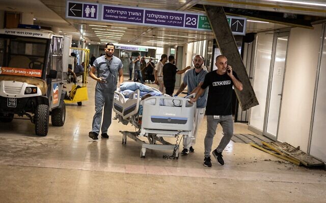 Des membres du personnel soignant mettant un patient en sécurité après qu'un bâtiment de l'hôpital Soroka a été touché par un missile iranien, à Beer Sheva, le 19 juin 2025. (Crédit : John Wessels/AFP) Des membres du personnel soignant mettant un patient en sécurité après qu'un bâtiment de l'hôpital Soroka a été touché par un missile iranien, à Beer Sheva, le 19 juin 2025. (Crédit : John Wessels/AFP)