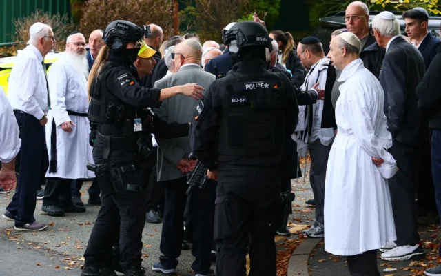 Des policiers armés discutent avec des membres de la communauté près de la synagogue Heaton Park Hebrew Congregation à Crumpsall, au nord de Manchester, le 2 octobre 2025 (Crédit : Paul Currie / AFP)