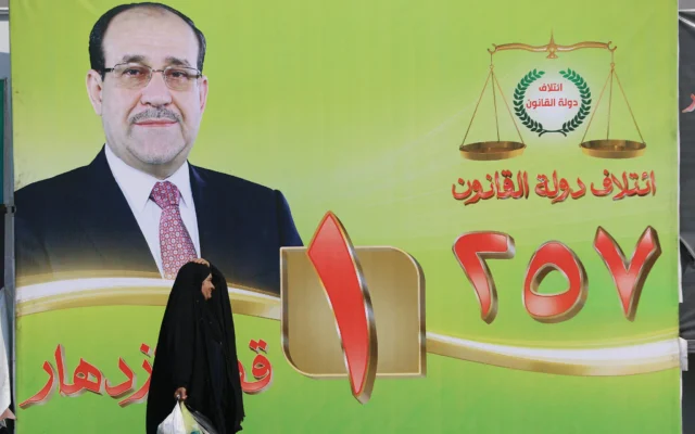 Une femme passe devant un panneau électoral arborant le portrait de l'ancien Premier ministre irakien Nouri al-Maliki dans le centre de Bagdad, en Irak, le 19 octobre 2025. (Crédit : AHMAD AL-RUBAYE / AFP) Une femme passe devant un panneau électoral arborant le portrait de l'ancien Premier ministre irakien Nouri al-Maliki dans le centre de Bagdad, en Irak, le 19 octobre 2025. (Crédit : AHMAD AL-RUBAYE / AFP)