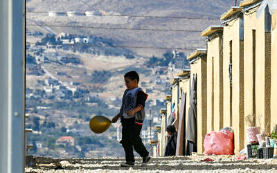 Un petit garçon avec son ballon devant les abris du complexe résidentiel Imam Ali, où des musulmans chiites libanais et syriens déplacés ont trouvé refuge à proximité de la ville d'Hermel, dans la vallée de la Bekaa, au nord-est du Liban, le 4 février 2026. (Crédit :  Joseph EID / AFP)