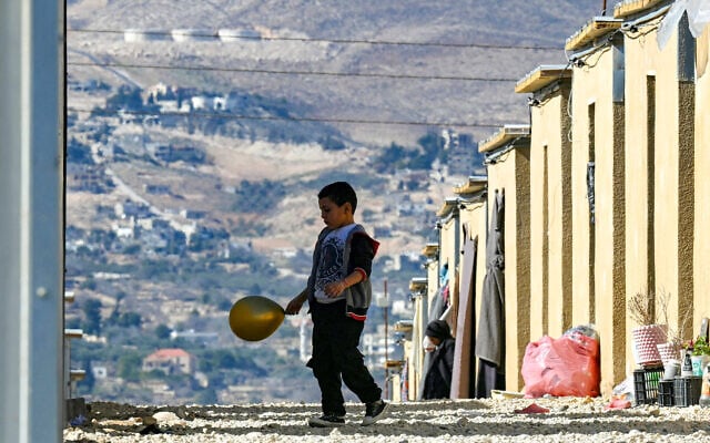 Un petit garçon avec son ballon devant les abris du complexe résidentiel Imam Ali, où des musulmans chiites libanais et syriens déplacés ont trouvé refuge à proximité de la ville d'Hermel, dans la vallée de la Bekaa, au nord-est du Liban, le 4 février 2026. (Crédit :  Joseph EID / AFP)