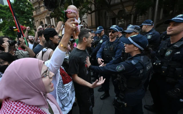 Des policiers se tiennent devant des manifestants pro-palestiniens et anti-israéliens lors d'une manifestation contre la visite du président Isaac Herzog en Australie à Sydney le 9 février 2026. (Crédit : Saeed Khan / AFP) Des policiers se tiennent devant des manifestants pro-palestiniens et anti-israéliens lors d'une manifestation contre la visite du président Isaac Herzog en Australie à Sydney le 9 février 2026. (Crédit : Saeed Khan / AFP)