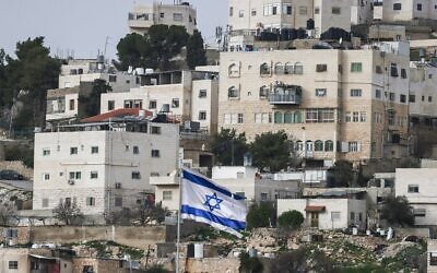 Un drapeau d'Israël flottant au-dessus de l'implantation de Beit Romano (non visible), avec des bâtiments palestiniens en arrière-plan, dans la ville de Hébron, en Cisjordanie, le 9 février 2026. (Crédit : Hazem Bader/AFP)