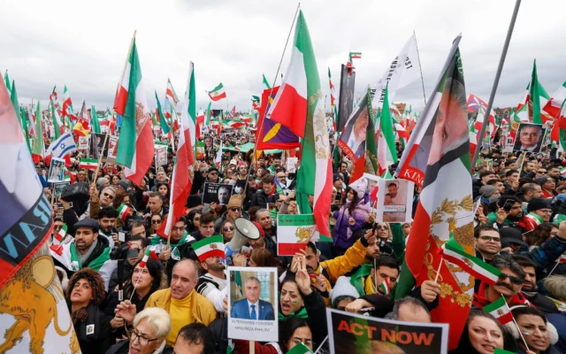 Les participants brandissent des drapeaux, parmi lesquels le drapeau national historique iranien représentant un lion et un soleil, ainsi que des affiches représentant l'ancien prince héritier d'Iran et désormais figure clé de l'opposition, Reza Pahlavi, et le président américain Donald Trump, lors d'une manifestation de l'opposition iranienne le 14 février 2026 au parc des expositions Theresienwiese à Munich, dans le sud de l'Allemagne. (Crédit : Michaela STACHE / AFP) Les participants brandissent des drapeaux, parmi lesquels le drapeau national historique iranien représentant un lion et un soleil, ainsi que des affiches représentant l'ancien prince héritier d'Iran et désormais figure clé de l'opposition, Reza Pahlavi, et le président américain Donald Trump, lors d'une manifestation de l'opposition iranienne le 14 février 2026 au parc des expositions Theresienwiese à Munich, dans le sud de l'Allemagne. (Crédit : Michaela STACHE / AFP)