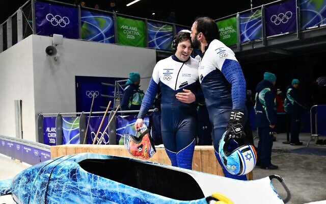 Les Israéliens Adam Edelman (à gauche) et Menachem Chen se félicitant mutuellement après avoir participé à la troisième manche de l'épreuve masculine de bobsleigh à deux au Cortina Sliding Center lors des Jeux olympiques d'hiver de Milan-Cortina 2026, à Cortina, le 17 février 2026. (Crédit : Stefano Rellandini/AFP)