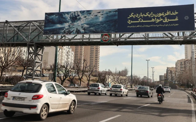 Des véhicules circulent sur une autoroute sous une banderole affichant la menace du guide suprême Ali Khamenei contre les navires de guerre américains, à Téhéran, le 18 février 2026. (Crédit : ATTA KENARE/AFP)