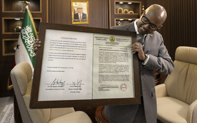 Le ministre de la Présidence de la République du Somaliland, Khadar Hussein Abdi, posant avec un certificat encadré contenant une déclaration signée de reconnaissance en tant qu'État par Israël lors d'une interview, à Hargeisa, le 21 février 2026. (Crédit : Tony Karumba/AFP)