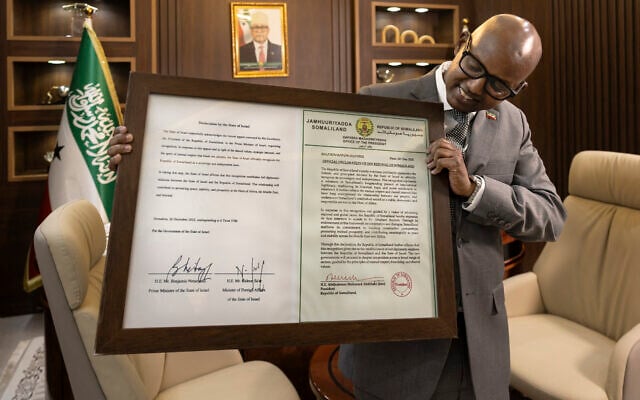 Le ministre de la Présidence de la République du Somaliland, Khadar Hussein Abdi, posant avec un certificat encadré contenant une déclaration signée de reconnaissance en tant qu'État par Israël lors d'une interview, à Hargeisa, le 21 février 2026. (Crédit : Tony Karumba/AFP)