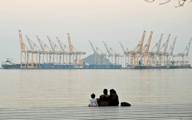 Une famille posant devant un chantier naval au large de la ville côtière de Fujaïrah, dans le détroit d'Ormuz, au nord des Émirats, le 25 février 2026. (Crédit : Giuseppe CACACE / AFP)