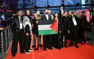 Le réalisateur palestinien Abdallah Alkhatib (2e à gauche) et l'équipe du film "Chronicles From the Siege" avec un drapeau palestinien à leur arrivée sur le tapis rouge de la cérémonie de remise des prix de la 76e Berlinale, le premier grand festival du film européen de l'année, à Berlin, le 21 février 2026. (Crédit : RALF HIRSCHBERGER / AFP)