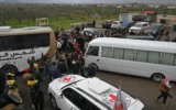 Des forces de sécurité et des responsables se rassemblent à côté de bus transportant des prisonniers lors d'une cérémonie d'échange de prisonniers entre les autorités syriennes et les combattants druzes, à Soueïda, en Syrie, le 26 février 2026. (Crédit : LOUAI BESHARA / AFP)