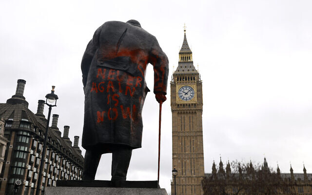 Le graffiti « Never again is now » (Plus jamais, c'est maintenant) sur une statue de l'ancien Premier ministre britannique Winston Churchill, sur Parliament Square, dans le centre-ville de Londres, le 27 février 2026. (Crédit : Brook Mitchell/AFP)