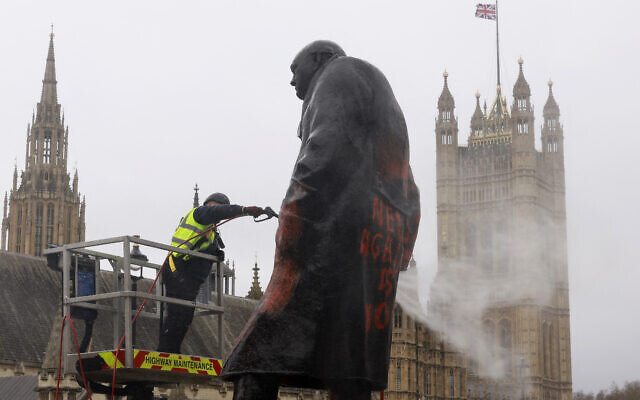 Un ouvrier nettoie  les graffitis sur la statue de l'ancien Premier ministre britannique Winston Churchill, sur Parliament Square, dans le centre de Londres, le 27 février 2026.  (Crédit : Brook Mitchell / AFP)