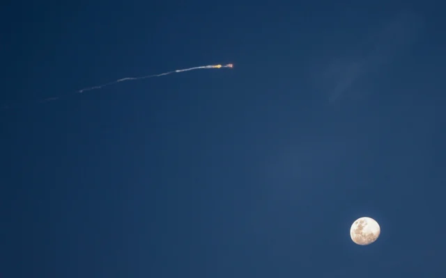 La lune est photographiée avant les traînées de fusées provenant d'une interception au-dessus du centre d'Israël le 28 février 2026. (Crédit : Jack GUEZ / AFP)