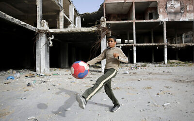 Un jeune garçon joue au football à côté d'une fresque murale peinte par l'artiste palestinien Ali Al-Jabali sur les vestiges d'un bâtiment partiellement détruit pendant la guerre de 2014 entre Israël et le Hamas, à Gaza, mardi 30 avril 2019. (AP Photo/Hatem Moussa)