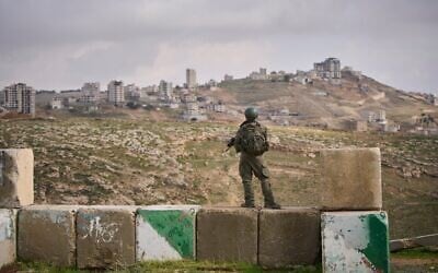Un soldat israélien montant la garde lors de la cérémonie d'inauguration de l'implantation nouvellement légalisée de Yatziv, près de la ville de Beit Sahour, en Cisjordanie, le 19 janvier 2026. (Crédit : Ohad Zwigenberg/AP)