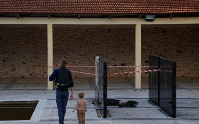 Des passants devant une plaque commémorative vandalisée au stand de tir de Kaisariani, dans la banlieue d'Athènes, en Grèce, le 16 février 2026. (Crédit: AP/ Petros Giannakouris)